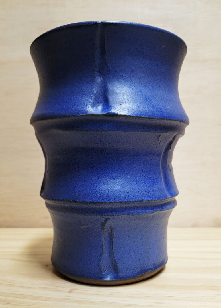 A blue vase sitting on top of a wooden table.