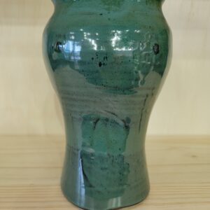 A green vase sitting on top of a wooden table.