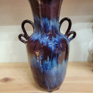 A blue and brown vase sitting on top of a wooden table.