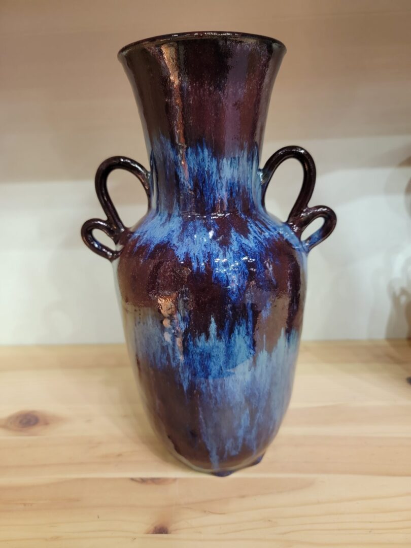 A blue and brown vase sitting on top of a wooden table.
