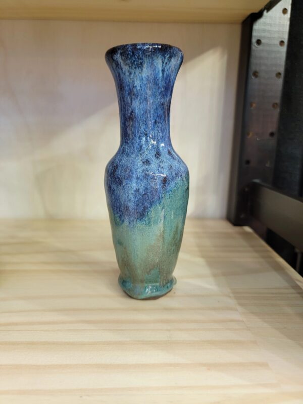 A blue vase sitting on top of a wooden table.