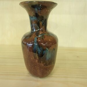 A brown vase with blue and black spots on it.