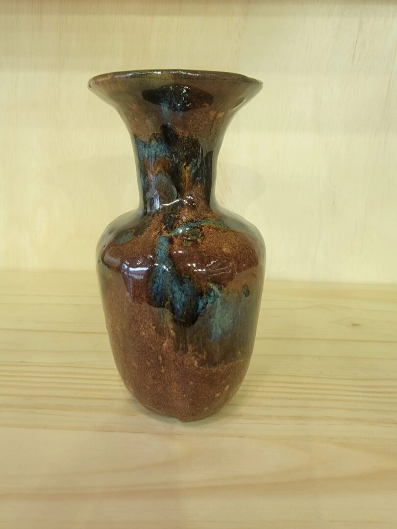A brown vase with blue and black spots on it.
