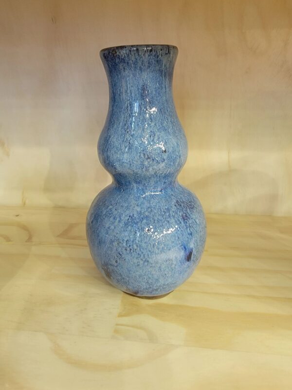 A blue vase sitting on top of a wooden table.