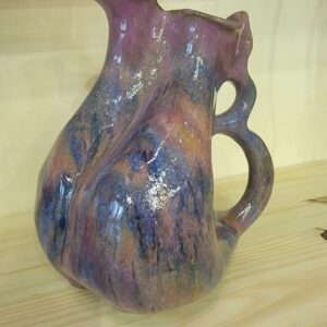 A purple and blue pitcher sitting on top of a table.