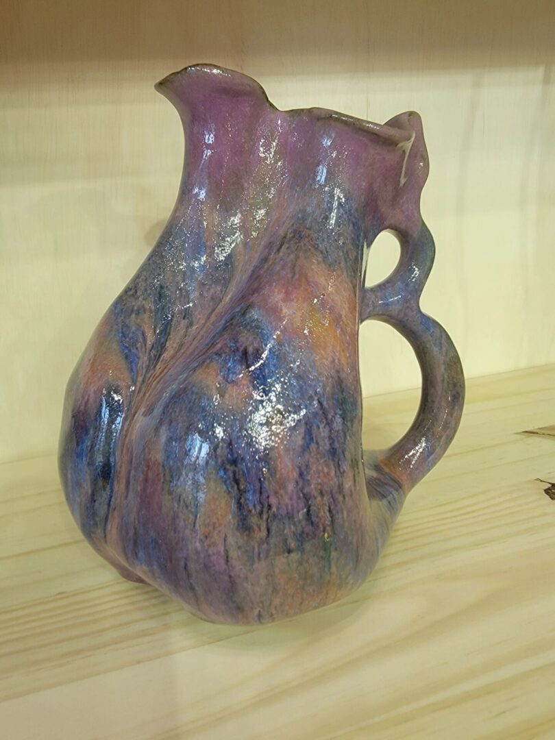 A purple and blue pitcher sitting on top of a table.