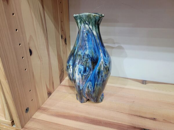 A blue and green vase sitting on top of a wooden table.