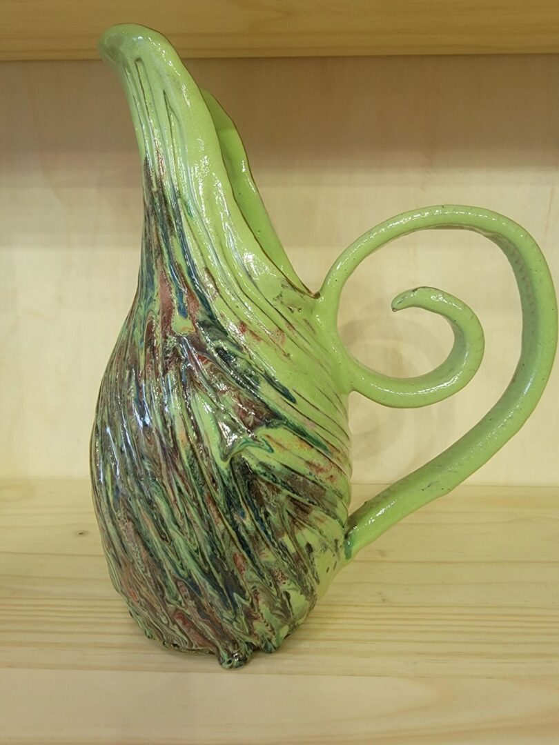 A green glass vase with a spiral handle.