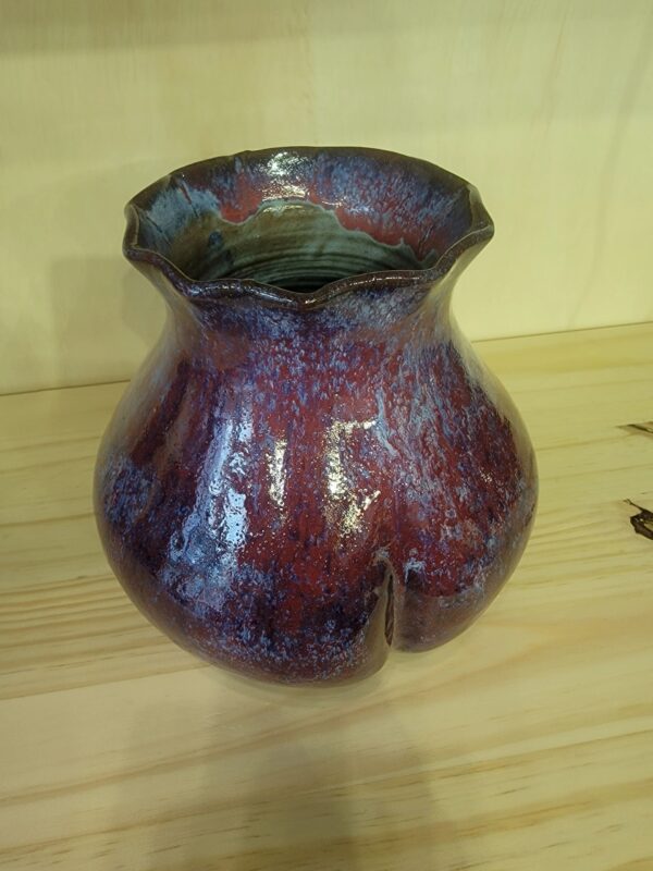 A purple vase sitting on top of a wooden table.