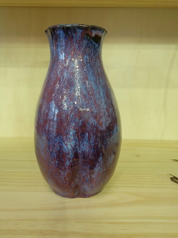 A purple vase sitting on top of a wooden table.