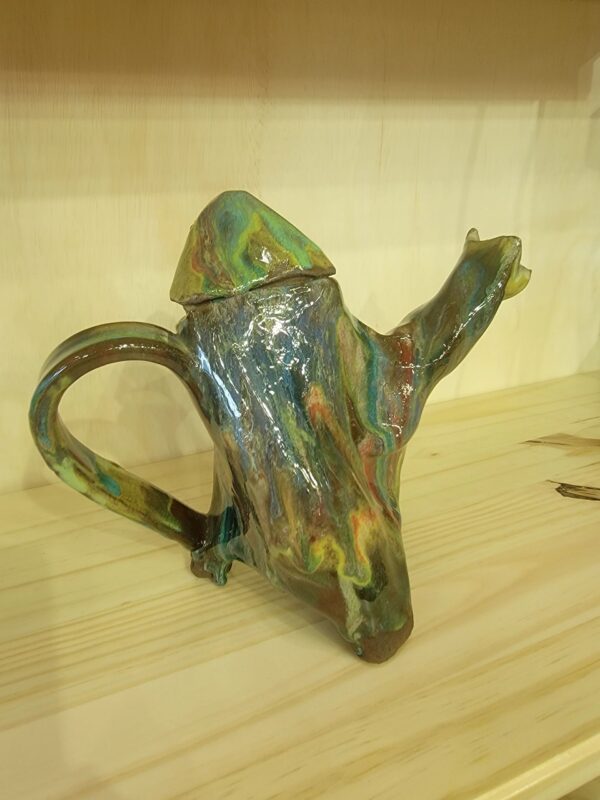 A green and brown teapot sitting on top of a table.