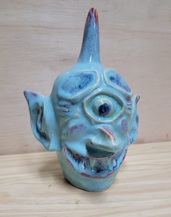 A blue ceramic face sitting on top of a wooden table.