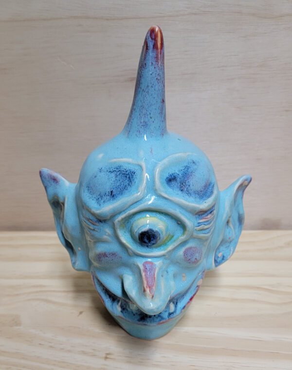 A blue ceramic head with horns and eyes.