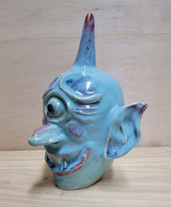 A ceramic sculpture of a clown 's head on top of a table.