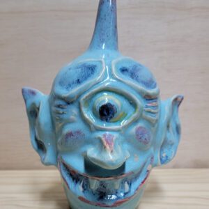 A blue ceramic face sitting on top of a wooden table.