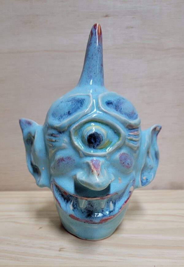 A blue ceramic face sitting on top of a wooden table.