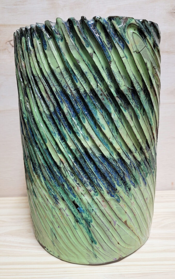 A green vase with some blue and black lines