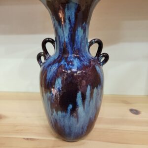 A blue and brown vase sitting on top of a wooden table.