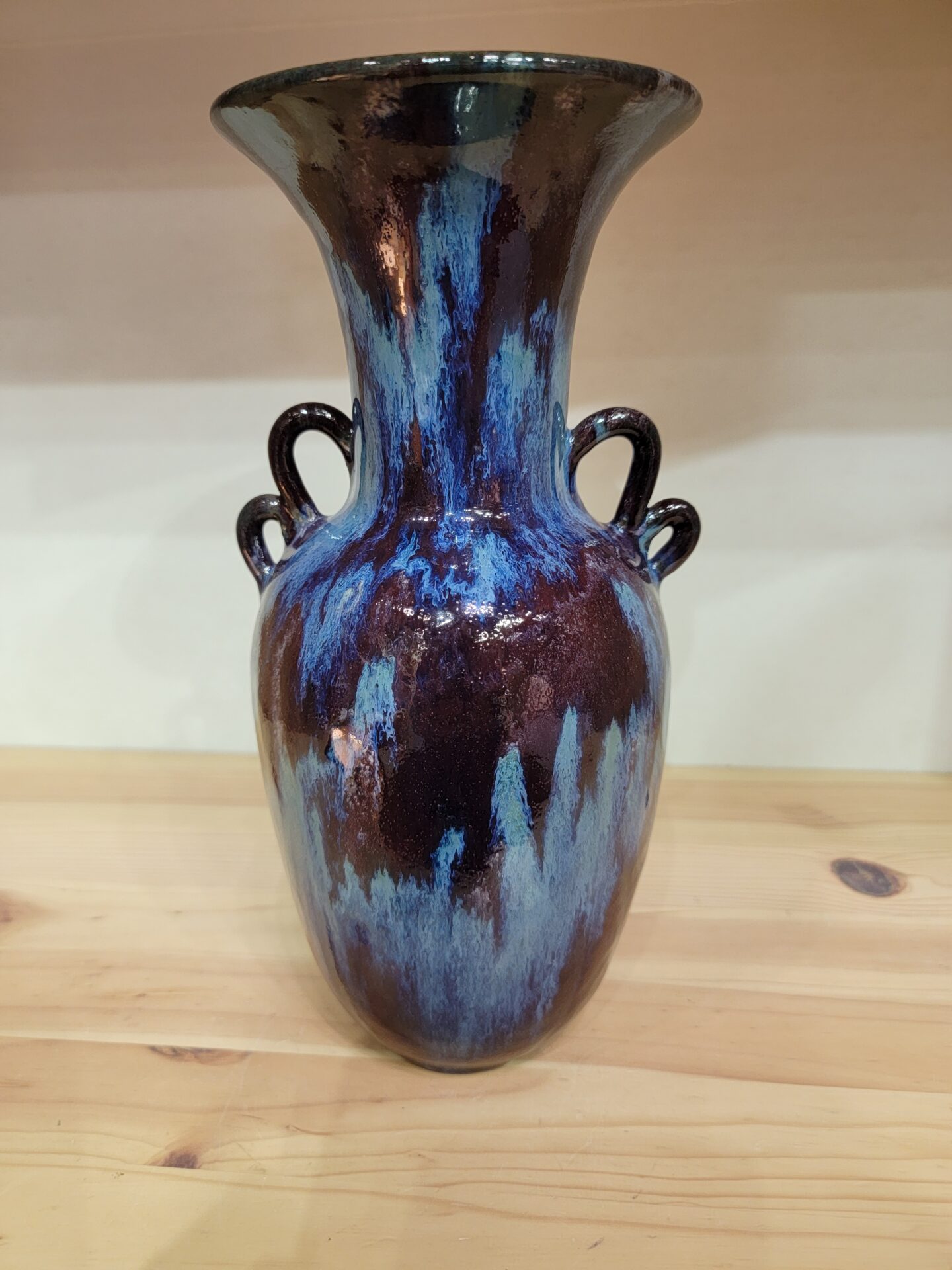 A blue and brown vase sitting on top of a wooden table.