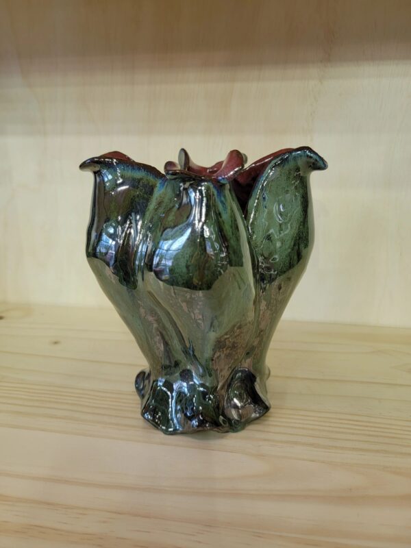 A green vase sitting on top of a wooden table.