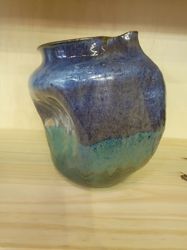 A blue and green vase sitting on top of a wooden table.