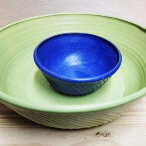 A blue bowl sitting in the middle of two green bowls.