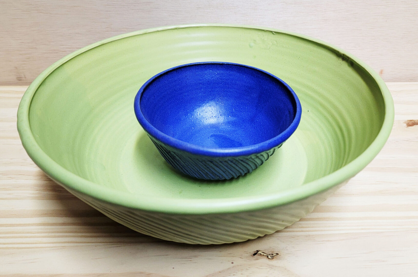 A blue bowl sitting in the middle of two green bowls.