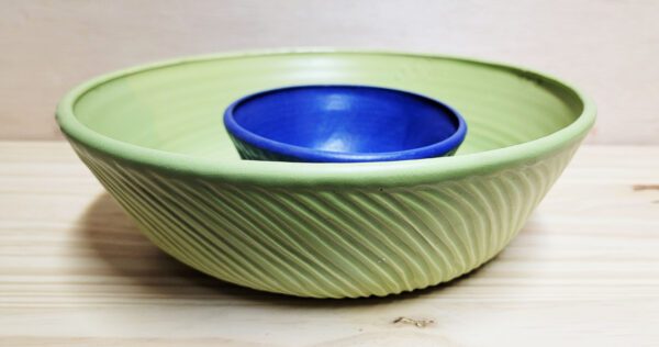 A green bowl with a blue bowl inside of it.