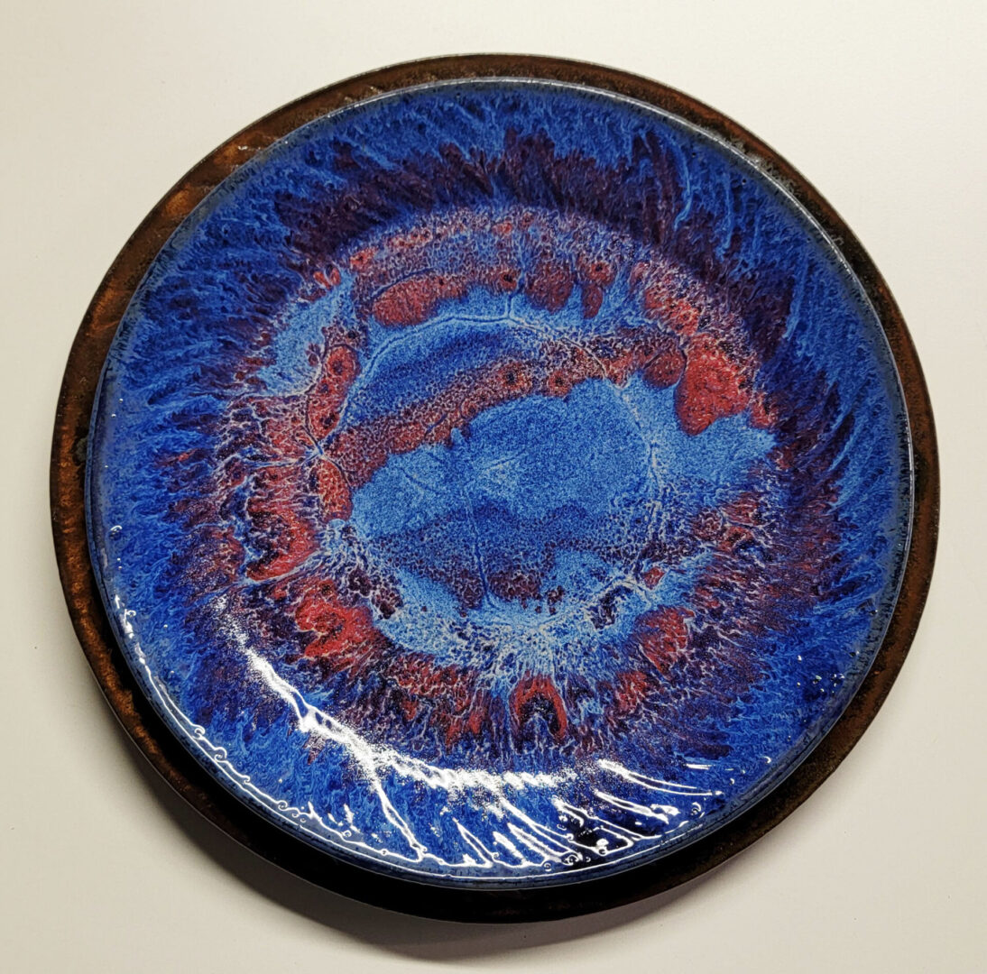 A blue plate with red and brown swirls on it