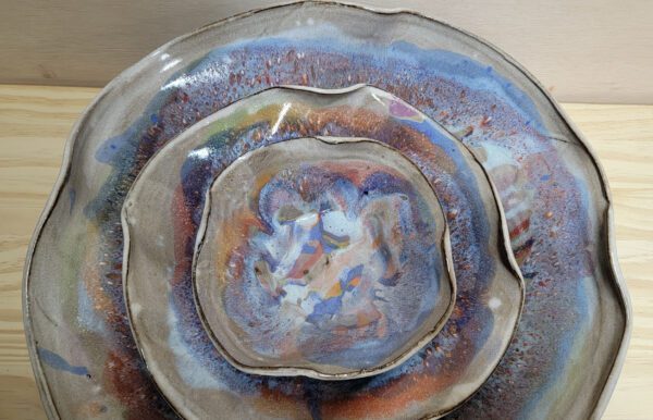 A bowl and plate with different colors of glaze.