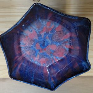 A blue bowl with red and purple design on it.