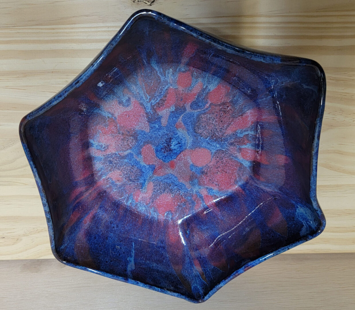 A blue bowl with red and purple design on it.