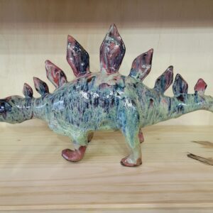 A ceramic stegosaurus figurine sitting on top of a table.