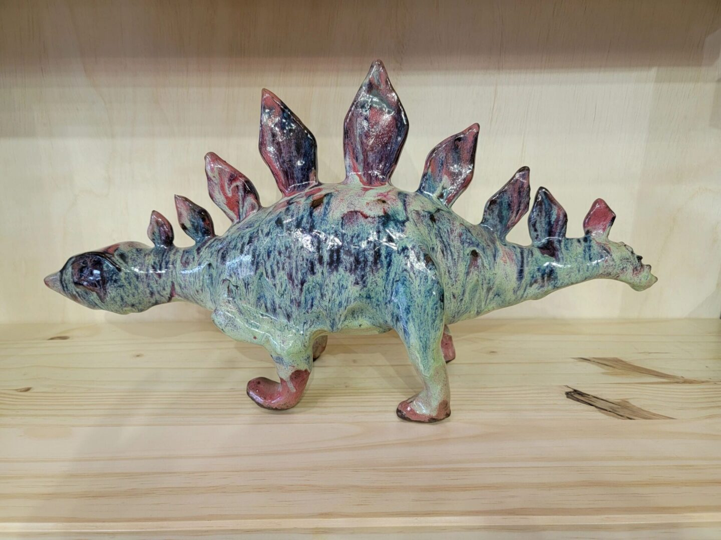 A ceramic stegosaurus figurine sitting on top of a table.