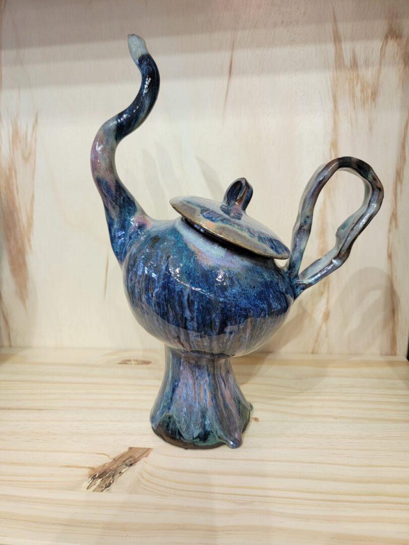 A blue teapot with two handles and a lid.