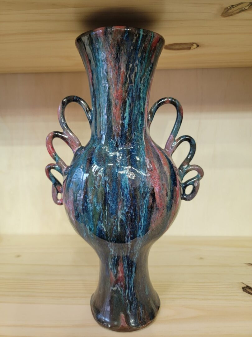 A blue vase with two handles on top of a table.