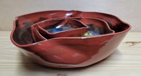 A red bowl with three different sized bowls in it.