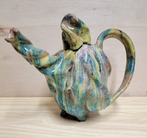 A ceramic teapot with a lizard design on the back.