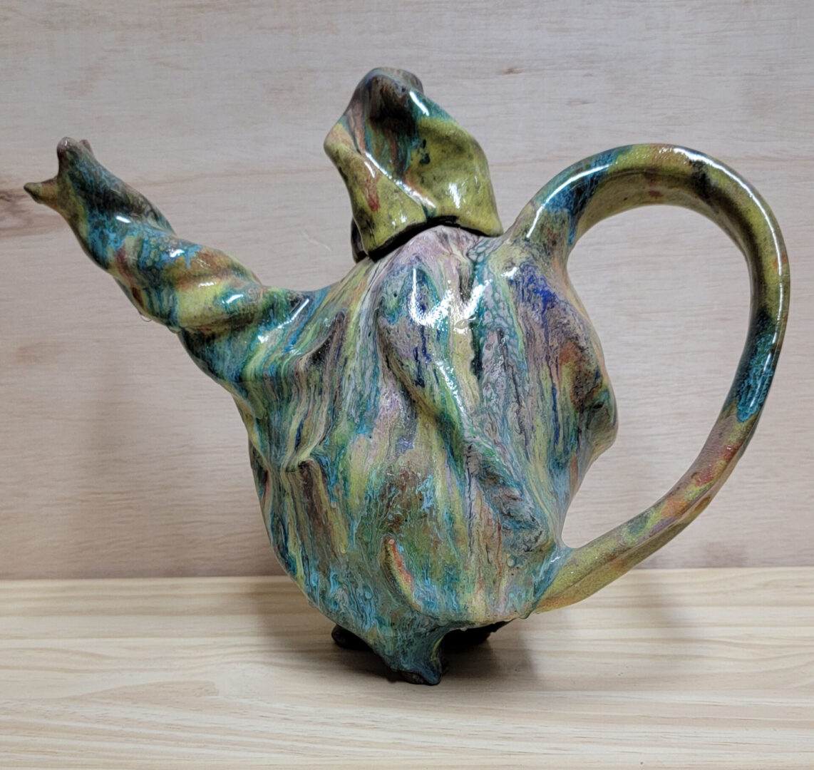 A ceramic teapot with a twisted handle and a lid.