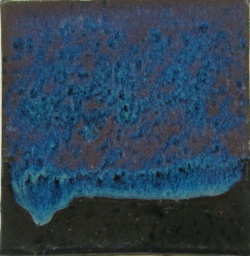 A blue and black tile with some brown on it