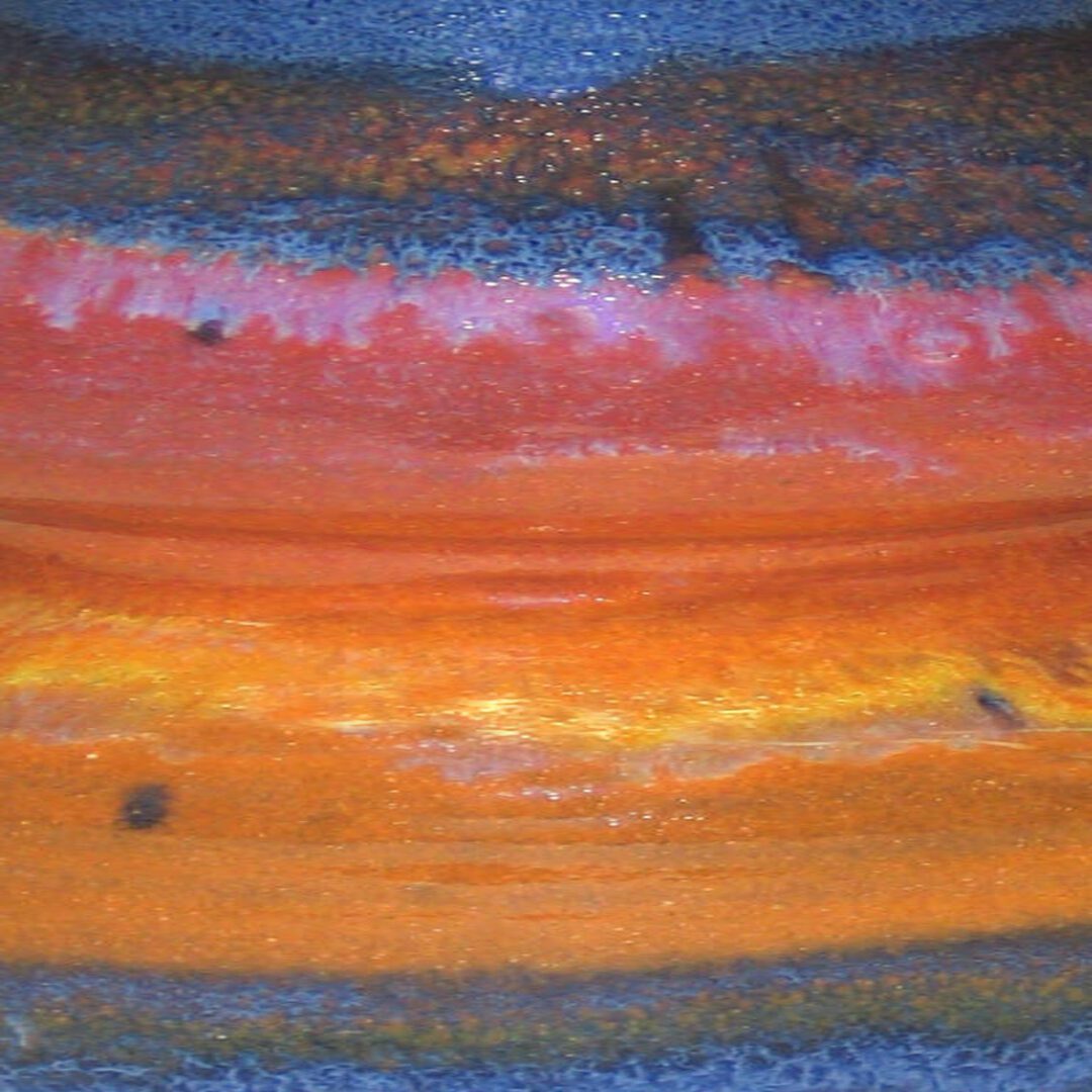 A close up of the orange and red paint on a painting.