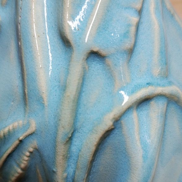 A close up of the blue glaze on a vase.