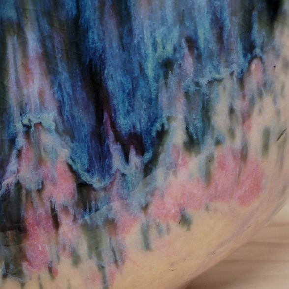 A close up of the blue and pink paint on a vase